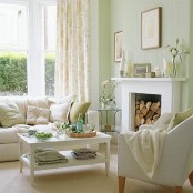 a serene spring living room with light green walls, a fireplace, artworks, blooms, floral textiles and green touches is very light and welcoming