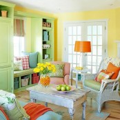 a cheerful living room with yellow walls, a green storage unit with pillows, orange touches and bold blooms
