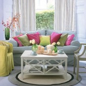 a pastel spring living room with a blue sofa and colorful and bright pillows, a yellow chair and bright blooms and candles