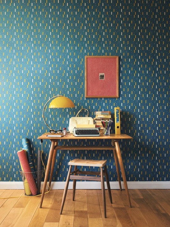 an elegant home office with plenty of color - dark green printed wallpaper, mid-century modern furniture, a yellow table lamp and a bold artwork is a lovely space to be in