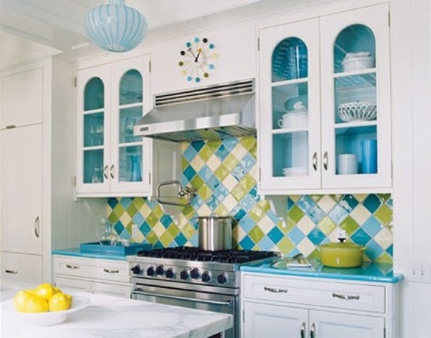 A white kitchen with shaker cabinets, with glazed cabinets, blue countertops and a green and blue geometric tile backsplash is a fun and bold idea
