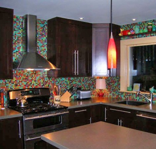 A dark stained kitchen with grey stone countertops and a super colorful mosaic tile backsplash is a fun idea