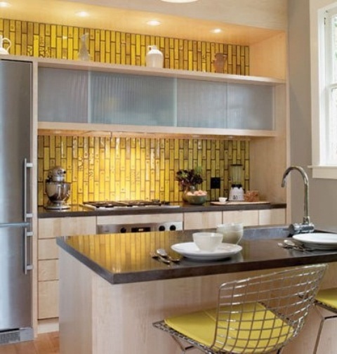 a sleek neutral kitchen with a yellow skinny tile backsplash and yellow chairs, with dark coutnertops and built-in lights is a stylish idea
