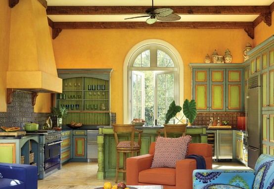 a colorful vintage kitchen in yellow, green cabinetry, blue cabinets, a large yellow hood and an orange chair