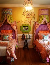 a colorful shared kids’ room with a yellow and white wall with paneling, purple upholstered beds with bright bedding, colorful canopies of fabric and bright artwork