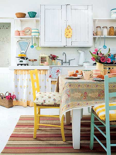 a cheerful ktichen with white cabinetry, bold yellow and blue chairs, floral textiles feels country and very relaxed