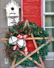 a fir wreath with berries and pinecones, a wooden star, oversized bells and plaid bows plus a bird house
