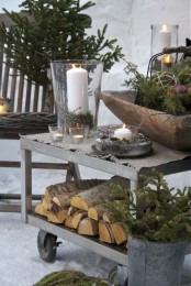 Nordic Christmas decor with firewood, fir branches, moss, candles is a great idea for a rustic and all-natural feel in your outdoor spaces