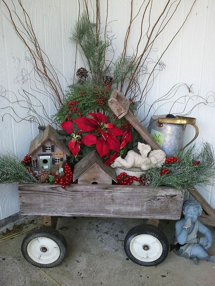 A wooden cart with berries, greenery, red blooms, branches, mini houses and a bucket will make your front porch rustic and cozy