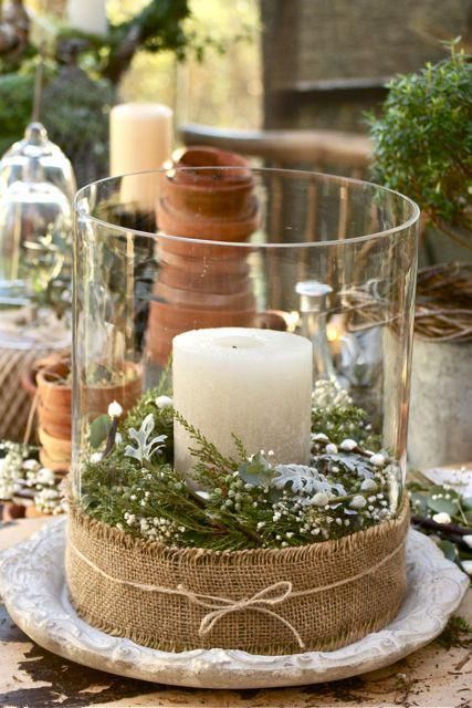 a glass jar with greenery and fir, with burlap around and a large candle can be used both indoors and outdoors