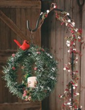 a fir branch sphere, with a candle, berries, a red bird on a stand interwoven with berries and greenery is chic