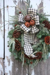 a fir wreath with pinecones, a plaid bow with bells and twigs is a chic and easy outdoor Christmas decoration