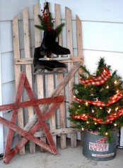 a wood plank star, a wooden door with skates, a mini Christmas tree with lights and burlap ribbons in a bucket for a rustic and vintage feel