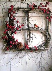 a window frame made of berries, twigs, pinecones and birdies looks very natural and very bright