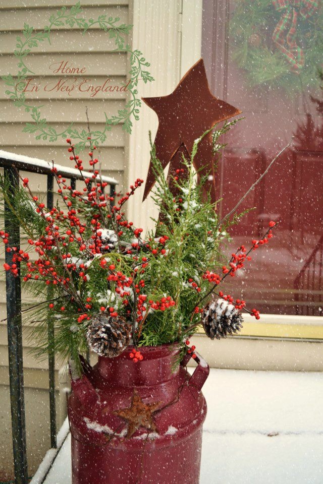 A red milk churn with greenery, berries, pinecones and a red star for a slight rustic and vintage feel in the space
