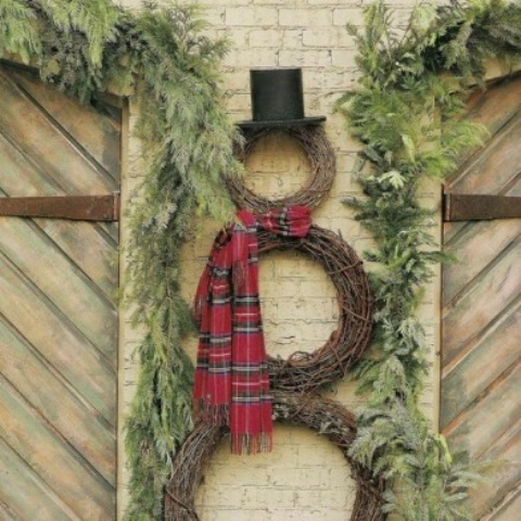 a snowman made of vine wreaths, a plaid scarf and a tall hat plus fir branches around for a slight rustic feel