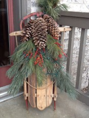 a vintage sleigh with fir branches, berries and oversized pinecones is a lovely rustic decoration for your front porch