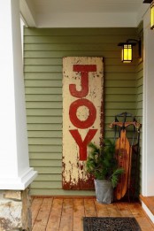 a shabby chic JOY sign, a bucket with fir branches and a vintage sleigh will make your front proch cozy and rustic