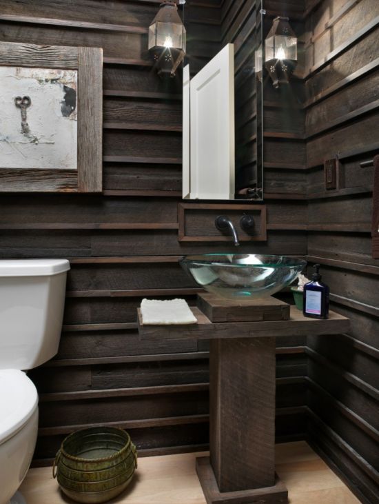 A dark stained sculptural wooden vanity matches the wood paneling on the walls and continues with the rustic style of the space