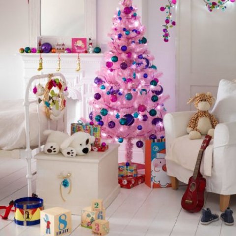 A white kids' room with bright Christmas decor   a bright pink Christmas tree with colorful ornaments, bright ornaments on the mantel and bright flowers hanging down from the ceiling