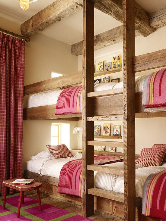 A cozy rustic kids' room with four built in bunk beds, with a ladder and pink and white bedding, with matching curtains and a rug