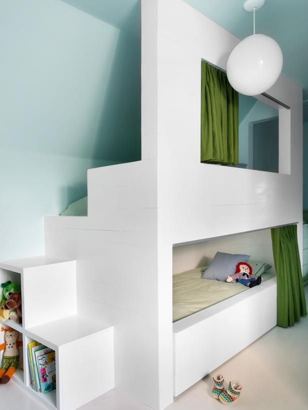 A small kids' room with aqua walls, with a built in bunk bed and neutral bedding, with curtains for privacy and lots of toys and other stuff