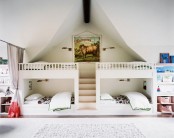 a small white kids’ room with four built-in bunk beds, neutral and pastel bedding, built-in storage units and baskets is a cool space