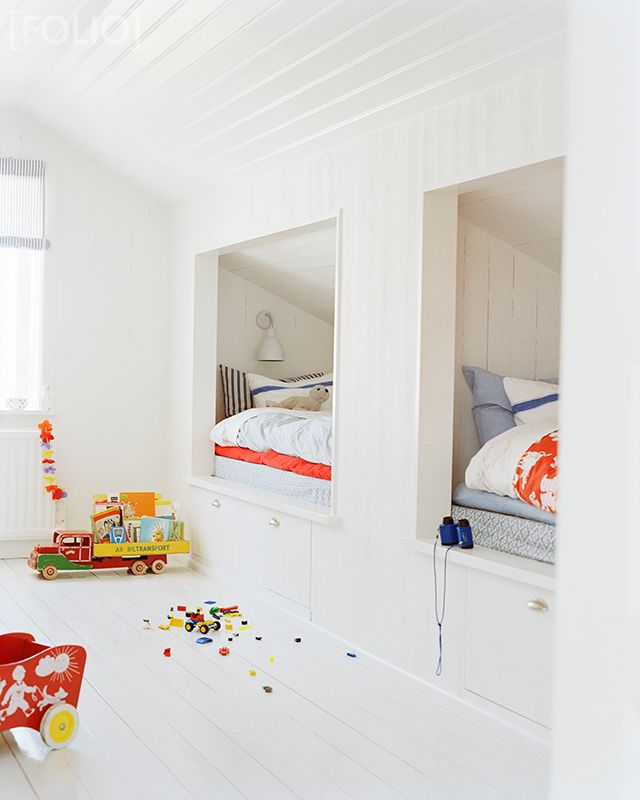 A white Scandinavian kids' room with built in bunk beds, with bright bedding, lots of natural light and colorful toys is ultimate