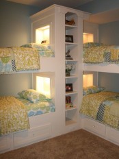 a traditional pastel bedroom with white built-in bunk beds and a shelving unit in the center, built-in lights and bright bedding