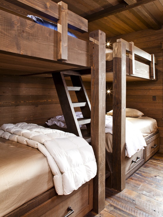 a stained rustic kids' room with four built-in bunk beds, with ladders and lights plus elegant neutral bedding