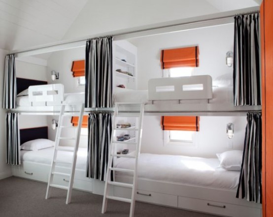an ultra-modern kids' room with four built-in bunk beds, with grey curtains, orange touches and seaside inspired sconces