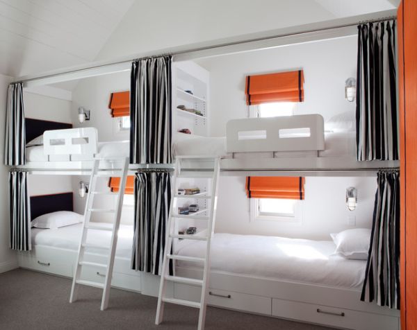 An ultra modern kids' room with four built in bunk beds, with grey curtains, orange touches and seaside inspired sconces