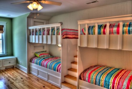a neutral kids' room with a green accent wall, white built-in bunk beds and bright bedding is amazing for kids