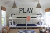a neutral kids’ room with beadboard walls, four white bunk beds, navy and white bedding, metal pendant lamps and woven lampshades