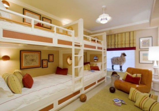 a bright kids' room in yellow, red and white, with four built-in bunk beds, bright bedding, an orange chair, bright yellow and red textiles