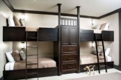 a stylish kids’ room with white walls, dark-stained built-in bunk beds with matching ladders and neutral bedding is cool