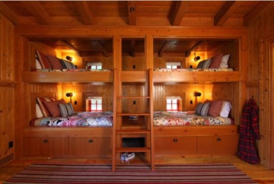 a rustic kids' room clad with wood, with four built-in bunk beds with ladders, with lights and colorful bedding is a cozy idea