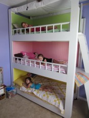 a colorful kids’ room with a bunk bed and painted walls inside each space plus a ladder and colorful bedding
