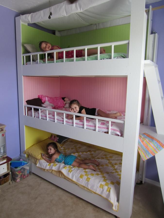A colorful kids' room with a bunk bed and painted walls inside each space plus a ladder and colorful bedding