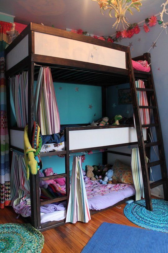 a colorful kids' room with a bunk bed for three, colorful bedding, rugs and curtains and a ladder for easy getting to the top