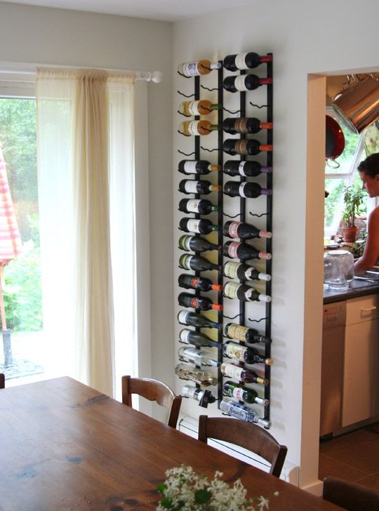 A wall mounted metal shelf with holders for wine bottles can be hung in the kitchen or dining room