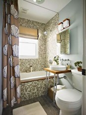a catchy small bathroom with mosaic tiles, frosted glass, a vanity on hairpin legs and a printed curtain