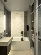 a grey and white bathroom done with small and catchy tiles, a square sink and tub and built-in storage space