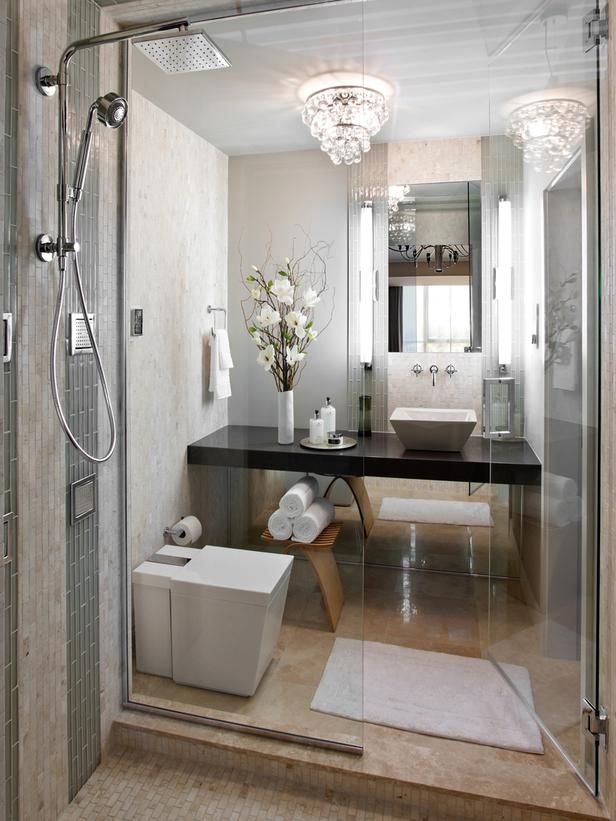 A refined small bathroom with stone tiles, a crystal chandelier, a shower space and a built in dark vanity