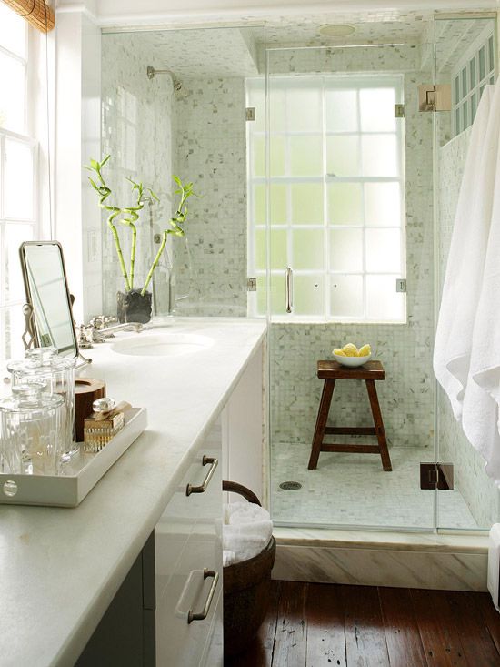 A cozy small bathroom with a large vanity and a built in sink, a dark stained floor, a light green shower space
