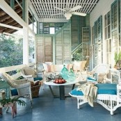 a vintage beach patio with white wicker furniture, striped blue and white upholstery, potted greenery and shutters on the walls