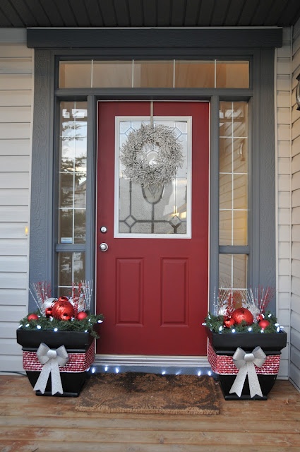 laconic Christmas porch decor with pots with silver and red ornaments, twigs, bells and silver bows plus a silver wreath
