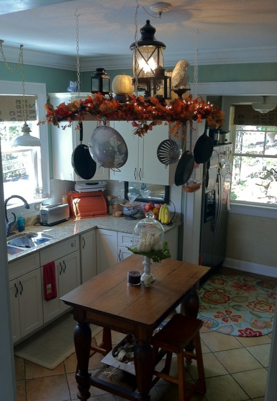 a suspended shelf with bright faux leaves, pumpkins and porcelain figurines for a fall kitchen