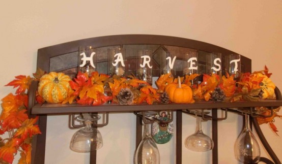 faux leaves, pumpkins and pinecones placed on a shelf is a very cool rustic-inspired idea