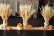 wheat arrangements, faux pumpkins and a burlap table runner for a stylish rustic tablescape